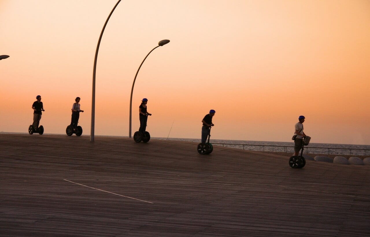 An image capturing the exhilarating speed of a Segway as it zooms along a sun-drenched coastal road, with the wind gently tousling the rider's hair and the vibrant turquoise ocean gleaming in the background